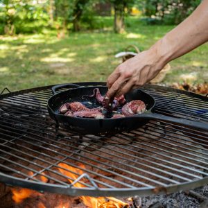 A vibrant outdoor grilling scene with octopus being prepared in a pan over an open flame.