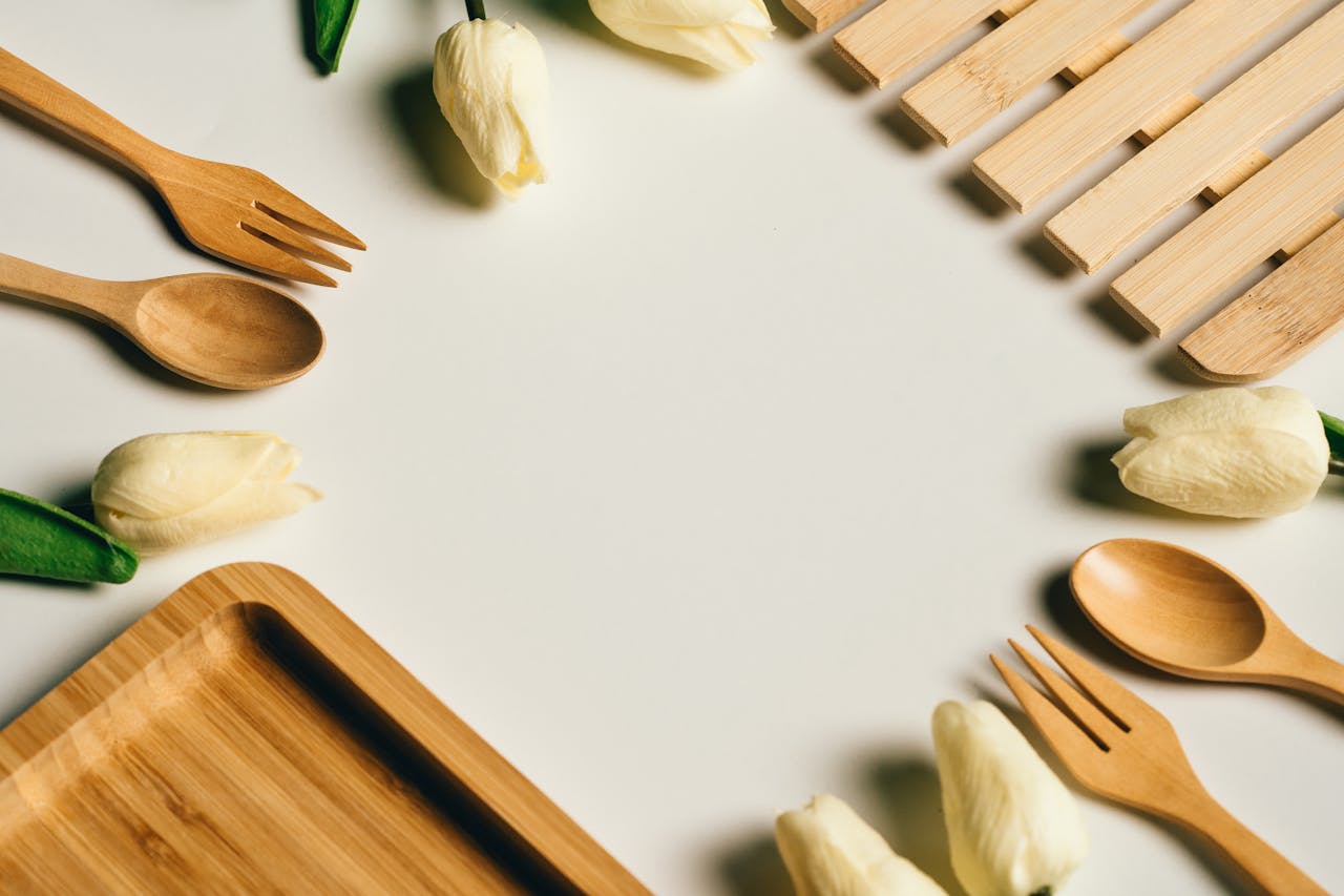 Aesthetic arrangement of wooden utensils and white tulips on a white background offering ample copyspace.