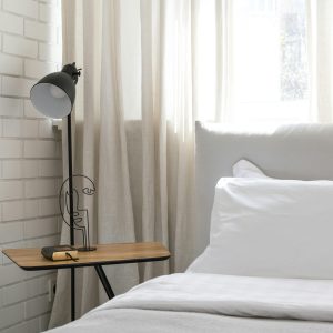 Inviting minimalist bedroom interior with a cozy atmosphere, featuring a soft bed and elegant side lamp.